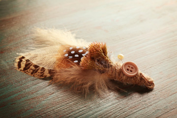 Beautiful feather boutonniere on color wooden background