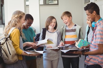 Group of smiling students standing with notebook in corridor