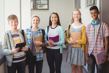 Portrait of smiling students standing with notebook 