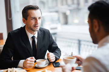 Confident lawyer consulting his client in cafe
