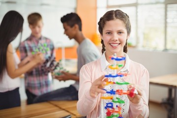 Smiling schoolgirl examining the molecule model 