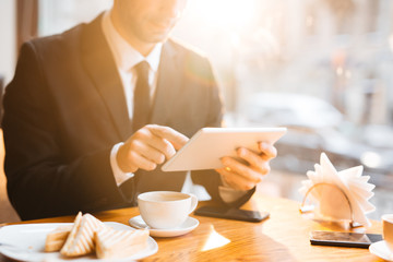 Modern businessman looking through online data in cafe