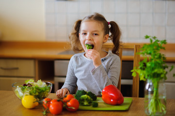 Little girl eating broccoli.