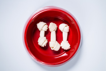 Three dog bones in feeding bowl isolated on white background