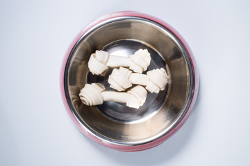 Three dog bones in feeding bowl isolated on white background