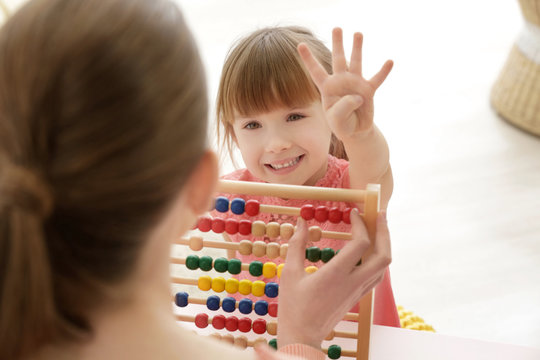 Cute little girl learning to count at private teacher's office