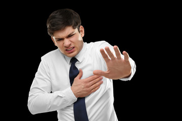 Heart attack concept. Young man suffering from chest pain on black background