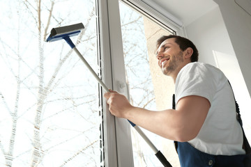 Young man washing window in office
