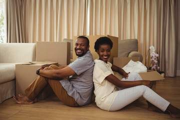 Portrait of couple sitting back to back in living room
