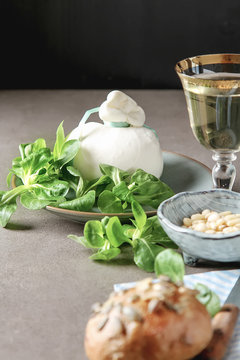 Italian fresh burrata cheese in a ceramic mash with green salad and olive oil. Dark background.