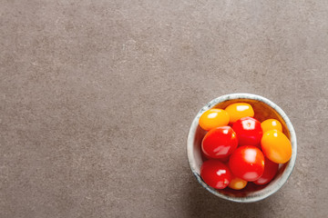 Fresh ripe cherry tomatoes in a ceramic bowl. Dark gray background.