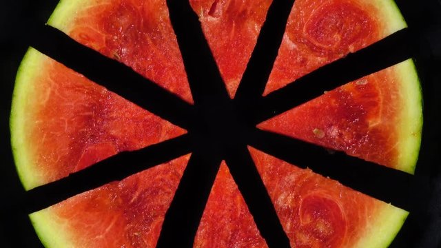 Excellent top view of fresh red water melon, rotating against the clock. Flat lay of radial segment pieces on black background with amazing texture in 4k, 3840x2160, clip. Eco product for healthy food