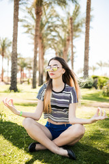 A young woman sitting on grass and enjoy summer sun on resort. Summer vocation