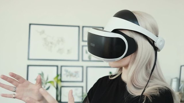 Beautiful young female playing game in virtual reality glasses. Beautiful woman touch something using modern virtual reality glasses