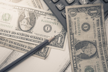 Calculator with american dollars on the wooden table background, finance concept, pencil, phone