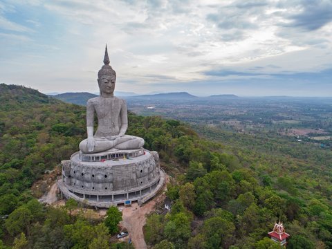 aerial view of Big Buddha sitting image on mountain with blue sky clouds at mukdahan province, Thailand.