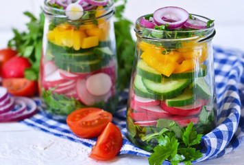 Vegetable salad with spinach and red onions in a glass jar on a white background