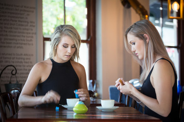 Close up image of two young girlfriends enjoying a cup of coffee in a trendy coffee shop