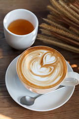 latte art coffee with tea on wood background