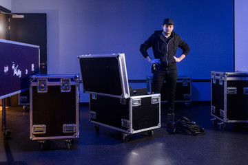 Roadie standing next to an unpacked flightcase - obrazy, fototapety, plakaty