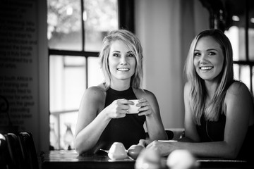 Close up image of two young girlfriends enjoying a cup of coffee in a trendy coffee shop