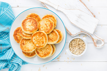 Cottage cheese pancakes with oats, syrniki on white rustic background