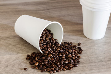 Paper cup and coffee beans on the wooden background