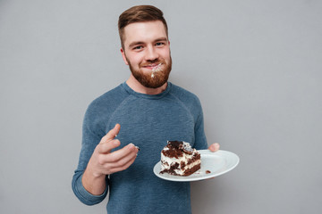Happy smiling bearded man eating chocolate cake