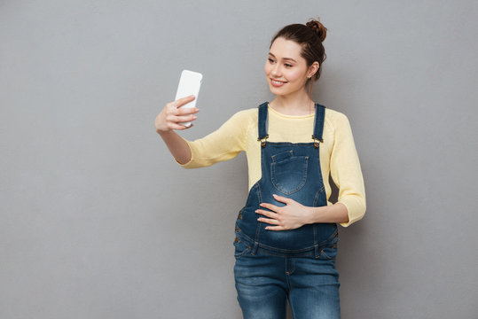 Portrait of a pregnant woman making selfie photo on smartphone