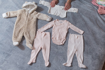 Baby's clothes laid out on bed, natural light.