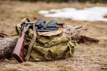 Foto op Canvas .Set van militaire jachtuitrusting met geweer in het bos tijdens het jachtseizoen. Bushcraft-, jacht- en wapenconcept © kaninstudio