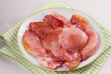 Bacon on white plate. Grilled rashers