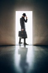 Man silhouette standing in the light of opening door in dark room