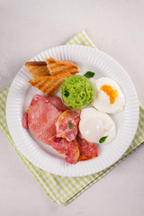 Bacon, poached eggs, mashed peas and toasts on white plate. Grilled rashers and eggs
