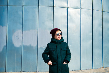 модный мальчик в солнечных очках и зимней куртке улыбается