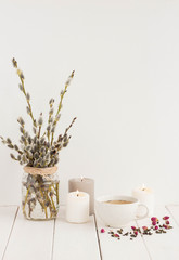 Flowers composition. White candles, grean tea, rose and willow branches on white wooden background