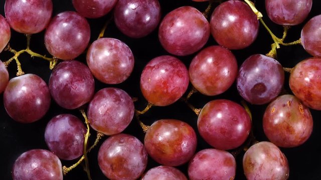 Excellent top view of grape berries with stems, rotating against the clock. Flat lay of yummy fruit dessert on black background with amazing texture in 4k, 3840x2160. Eco product for healthy food.