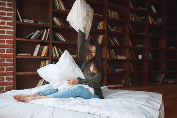 Beautiful young woman embracing pillow on bed in the morning at home