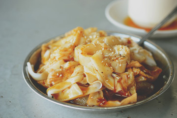 traditional malaysian chinese chee chong fun made of rice noodle, fried beancurd skin, served with sweet soya bean sauce with roasted sesame seed as garnishment on top.