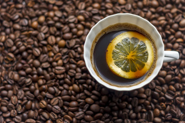cup of coffe with lemon on coffe beans background