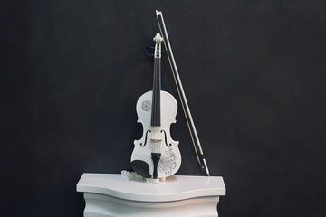 White violin on a pedestal on a black background. Music © DmyTo