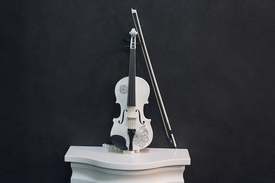 White violin on a pedestal on a black background. Music