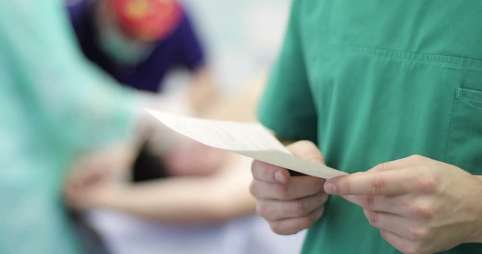 4K The doctor reads the patient's medical history on a background operation.