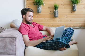 Young Caucasian man using his lap top  at his home.