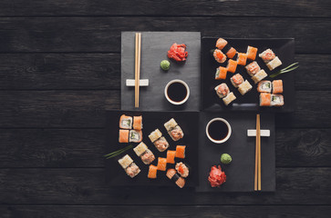 Set of sushi maki and rolls on black rustic wood, top view