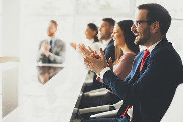 Smiling business group clapping hands at the meeting