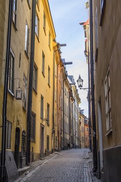 foot walk on narrow street of Stockholm in afternoon. High walls of close standing houses © nordberry