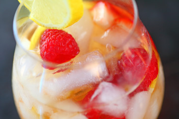 Closeup view of white wine with ice, lemon and raspberries