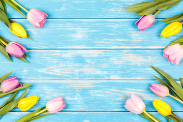 Fototapeta na wymiar View of bunch of yellow and pink tulips on a blue wooden background
