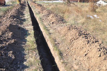 Digging a trench. Earthworks, digging trench. Long earthen trench dug to lay pipe or optical fiber.